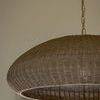 Close side profile of lit wicker pendant showing shadow details and room background