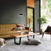 Wider angle of Elliot Granite Rug with additional stack of folded textiles near sofa and decorative pillows