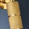 Close-up of Truett Wall Sconce knurled cylinder light and hinge detail against dark blue wall background