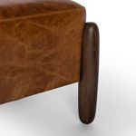 Close-up on ottoman side leg showing the smooth vintage parawood texture against leather
