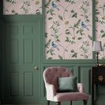 Nuit Blush wallpaper applied on wall panels in a room with green painted doors, a mauve tufted armchair, and a side table ...