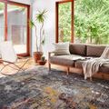 Samra dark grey spice rug styled in modern living room with sofa, chair, and large windows