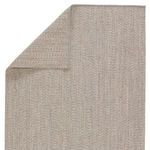 Top corner of rug folded over revealing reverse side with same woven texture and color