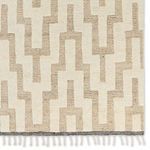 Close-up of rug edge highlighting fringe and woven black and cream border trim
