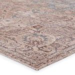 Close-up angled view showing rug’s low pile and woven polyester texture in faded tan and blue tones