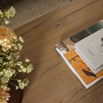 Styled vignette showing stacked books and flowers on table top highlighting natural wood finish