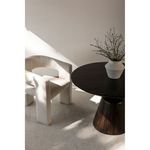 Side angle of Elo Chair next to round dark wood table with decorative vase in bright room