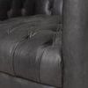 Side close-up of tufted leather seat cushion and smooth armrest detail in ebony finish