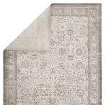 Duplicate of Odel rug folded to reveal solid light gray backing and front faded traditional floral pattern