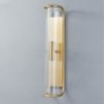 Lit sconce view showing warm illumination inside ribbed glass and polished nickel frame on gray wall