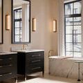 Bathroom setting with two Blaine sconces lit beside black framed mirrors and marble tub