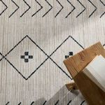 Close-up of rug pattern next to wooden bench with book, highlighting fine woven details