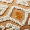 Close-up on raised thick ivory cotton yarn loops and woven mustard diamond detail on peach fabric