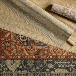 Rolled rugs layered on top of each other, highlighting different traditional pattern styles and color schemes.