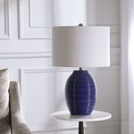 Luke Table Lamp angled slightly more to the side on a white round side table near a beige couch