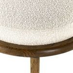 Side angle profile focusing on frame leg and metal stretcher under boucle cushion