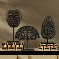 Three black ornamental sculptures on stands placed atop smaller wood and composite box