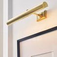 Angled close-up showing cylindrical brass bar and mounting bracket of picture light