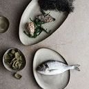 Overhead view of various Muubs oval plates and bowls with food presented