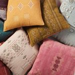 Assortment of pillows including mustard yellow tribal embroidered pillow among others with varied colors and patterns