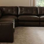 Modular sectional arrangement in room with tufted leather cushions and matching espresso color