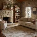Townes Sand Beige rug styled in cozy living room with stone fireplace, beige sofa, and wooden ceiling