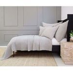 Side view of bed with Vancouver Sham, gray walls, light rug, and a wooden nightstand with green plant