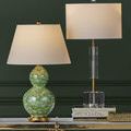 Deville Table Lamp displayed next to green double-gourd lamp on gold and glass console table with dark green paneled wall