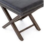 Fine close-up showing leather texture contrast against smooth dark wood of ottoman base