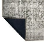 Corner of rug folded to reveal solid dark backing fabric