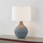 Nepperhand table lamp shown on a wooden surface against a light wall with light turned on