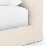 Close-up of cream linen upholstered bed corner with white pillow