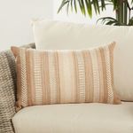 Lumbar pillow styled on light cream outdoor sofa with green plant in background