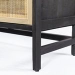 Close-up of black iron handle on woven cane door highlighting hardware finish