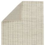 Folded corner revealing plain beige fabric backing on underside of the striped handwoven rug