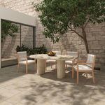 Sunlit outdoor dining setup with Luce chairs and stone table on light stone tile patio beside glass doors