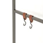 Close-up of two black metal S-hooks hanging from brown leather straps on frame bar