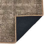 Close-up of rug corner flipped to show dark black backing and tight woven edge stitching