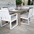 Set of six Newport Dining Chairs around a weathered wood outdoor dining table on patio flooring