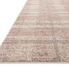 angled view showing thin pile height and soft edge binding of the plaid Ember Clay / Mist rug