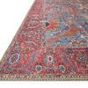 Close-up angled view highlighting the rug's red border with floral details and stitched edges