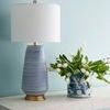 Console table styled with blue and white striped ceramic lamp and blue patterned tulip vase against pale blue wall