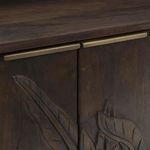Close-up on brass handles and carved leaf details on dark wood front doors