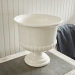 Side view of empty pedestal bowl on distressed gray surface with dark gray throw nearby