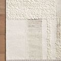 Corner of the rug on wood floor highlighting looped pebble texture and stitched border