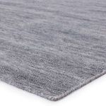 Close-up of rug corner showing low-pile woven texture with tight edge binding in gray-blue