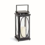 Tall black outdoor lantern with oval frames on glass panels and wide square base holding a white candle