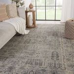 Gray rug styled in sunlit living room paired with neutral sofa, wooden side table, and wicker pouf