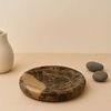 Brown Rivera Medium Tray styled on a beige surface with white vase and two gray stones in background