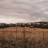 Wide landscape of Crazy Horse Country with dry grass foreground and rocky ridges under cloudy sky